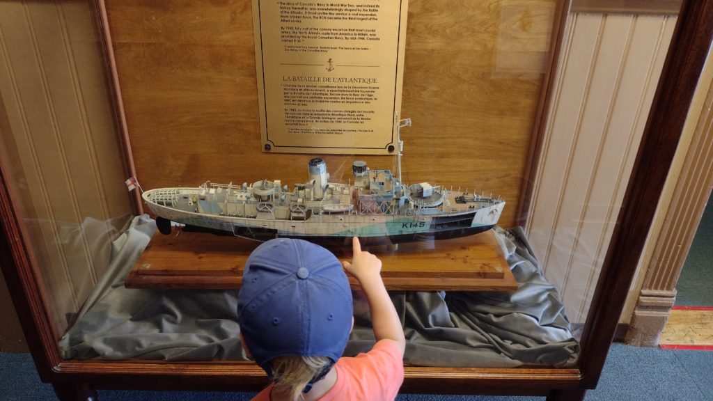 A small boy points at a model of a Flower Class Corvette