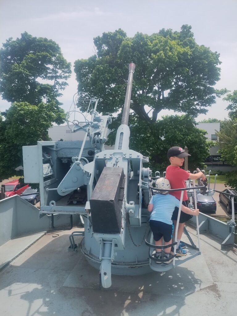 two boys on one side of a 40mm Anti aircraft gun